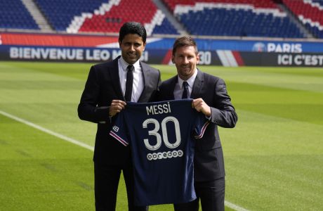 Lionel Messi, right, and PSG president Nasser Al-Al-Khelaifi hold Messi's jersey Wednesday, Aug. 11, 2021 at the Parc des Princes stadium in Paris. Lionel Messi said he's been enjoying his time in Paris "since the first minute" after he signed his Paris Saint-Germain contract on Tuesday night. The 34-year-old Argentina star signed a two-year deal with the option for a third season after leaving Barcelona. (AP Photo/Francois Mori)