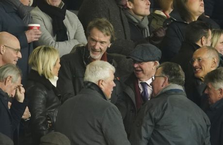 Businessman Jim Ratcliffe, centre top, and former Manchester United manager Sir Alex Ferguson, in the cap, seen on stands ahead of the English Premier League soccer match between Manchester United and Tottenham Hotspur at the Old Trafford stadium in Manchester, England, Sunday, Jan.14, 2024. (AP Photo/Dave Thompson)