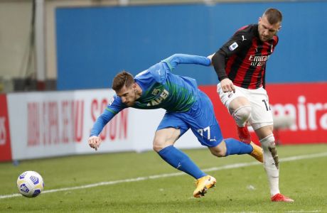 Sassuolo's Giorgos Kyriakopoulos, left, duels for the ball with AC Milan's Ante Rebic during the Serie A soccer match between AC Milan and Sassuolo at the San Siro stadium, in Milan, Italy, Wednesday, April 21, 2021. (AP Photo/Antonio Calanni)