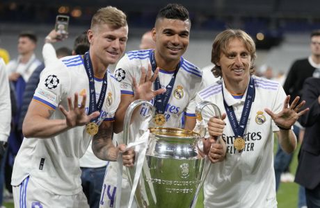 Real Madrid's Luka Modric, right, Real Madrid's Casemiro, center, and Real Madrid's Toni Kroos pose for a photograph with the trophy after winning the Champions League final soccer match between Liverpool and Real Madrid at the Stade de France in Saint Denis near Paris, Sunday, May 29, 2022. (AP Photo/Kirsty Wigglesworth)