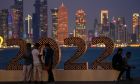 With the city skyline in the background, people pose for a photograph at the corniche in Doha, Qatar, Thursday, Nov. 17, 2022. Final preparations are being made for the soccer World Cup which starts on Nov. 20 when Qatar face Ecuador. (AP Photo/Hassan Ammar)
