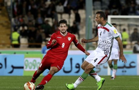 Iran's national soccer team player Jalal Hosseini, right, kicks the ball as Oman's Abdul Aziz Al-Maqbali follows him during a match  for the FIFA 2018 World Cup and AFC 2019 Asian Cup joint qualifiers, at Azadi Stadium in Tehran, Iran, Tuesday, March 29, 2016. (AP Photo/Vahid Salemi)