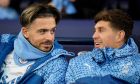 Manchester City's Jack Grealish, left, sits on the bench with his teammate John Stones prior to the start of the FA Cup quarterfinal soccer match between Manchester City and Newcastle at the Etihad Stadium in Manchester, England, Saturday, March 16, 2024. (AP Photo/Dave Thompson, Pool)