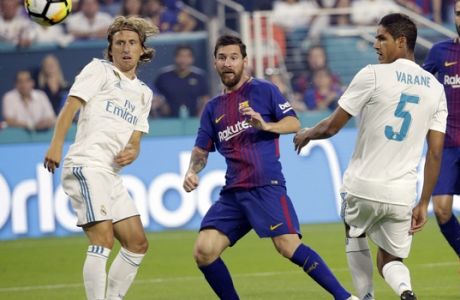 Barcelona's Lionel Messi, center, watches after kicking the ball for a goal as Real Madrid's Luka Modric, left, and Raphael Varane (5) look on during the first half of an International Champions Cup soccer match, Saturday, July 29, 2017, in Miami Gardens, Fla. (AP Photo/Lynne Sladky)