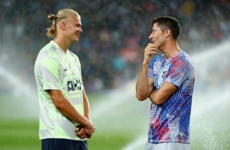Manchester City's Erling Haaland, left, speaks with Barcelona's Robert Lewandowski ahead of a charity friendly soccer match between Barcelona and Manchester City at the Camp Nou stadium in Barcelona, Spain, Wednesday, Aug. 24, 2022. (AP Photo/Joan Monfort)