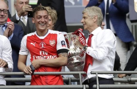 Arsenal team manager Arsene Wenger, right, holds the trophy next to Arsenal's Mesut Ozil after the English FA Cup final soccer match between Arsenal and Chelsea at the Wembley stadium in London, Saturday, May 27, 2017. (AP Photo/Matt Dunham)