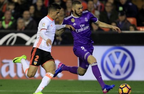 Real Madrid's Karim Benzema, background, duels for the ball with Valencia's Joao Cancelo, during the Spanish La Liga soccer match between Valencia and Real Madrid at the Mestalla stadium in Valencia, Spain, Wednesday, Feb. 22, 2017. (AP Photo/Alberto Saiz)