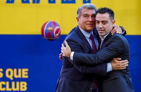 FC Barcelona's new coach Xavi Hernandez, right, embraces FC Barcelona president Joan Laporta during his official presentation at the Camp Nou stadium in Barcelona, Spain, Monday, Nov. 8, 2021. Xavi, who thrived in Barcelonas midfield alongside Messi and Andres Iniesta, was officially introduced as coach on the field of the Camp Nou with a reception usually only offered to top players. (AP Photo/Joan Monfort)