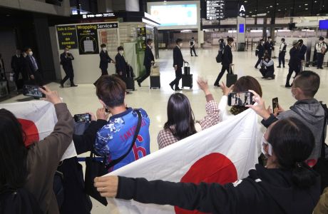 Fans cheer as part of Japan national soccer team arrive at Narita International Airport to fly to Qatar World Cup Wednesday, Nov. 9, 2022, in Narita near Tokyo. (AP Photo/Eugene Hoshiko)